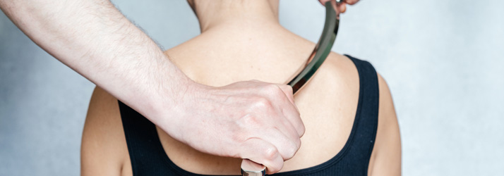 Chiropractic Lincoln NE Muscle Scraping A practitioner uses a sraping tool to rub across the upper back of a patient